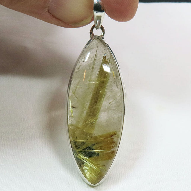 Gold Rutile in Clear Quartz Sterling Silver Pendant Jewelry held by a hand on a white background