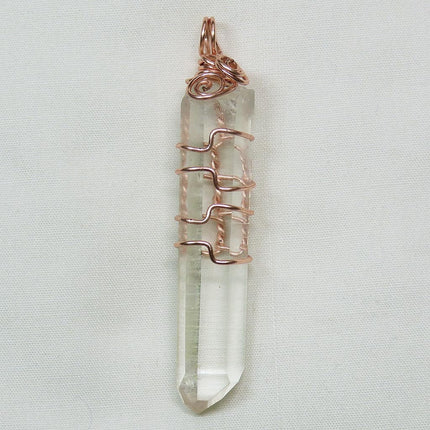Arkansas Quartz Crystal Point Wire Wrapped Pendant Jewelry on a light fabric background