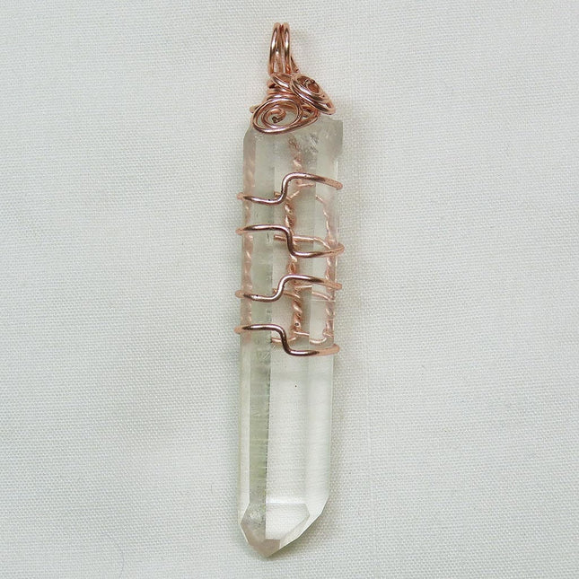 Arkansas Quartz Crystal Point Wire Wrapped Pendant Jewelry on a light fabric background