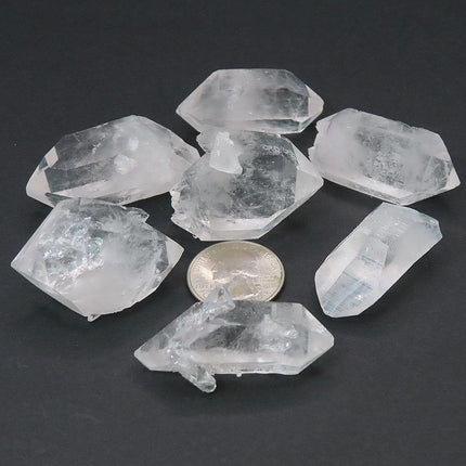 5 Arkansas Quartz Crystal Double Terminated Points & 2 DT/ET Points on a dark surface with a coin for scale