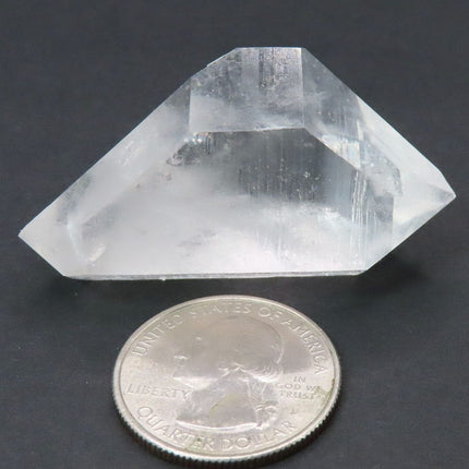 Arkansas Arkimer Style Quartz Crystal Double Terminated Point next to a quarter for scale on a dark background