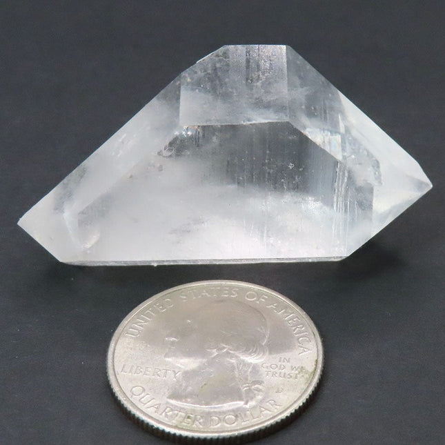 Arkansas Arkimer Style Quartz Crystal Double Terminated Point next to a quarter for scale on a dark background