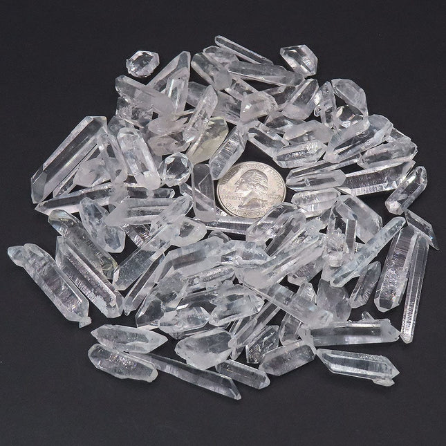 100 Arkansas A Grade Quartz Crystal Double Terminated Points with a quarter coin for scale on a dark background