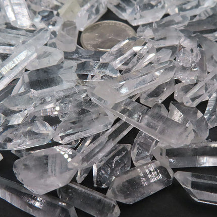 Close up of 100 Arkansas A Grade Quartz Crystal Double Terminated Points with a quarter coin for scale on a dark background