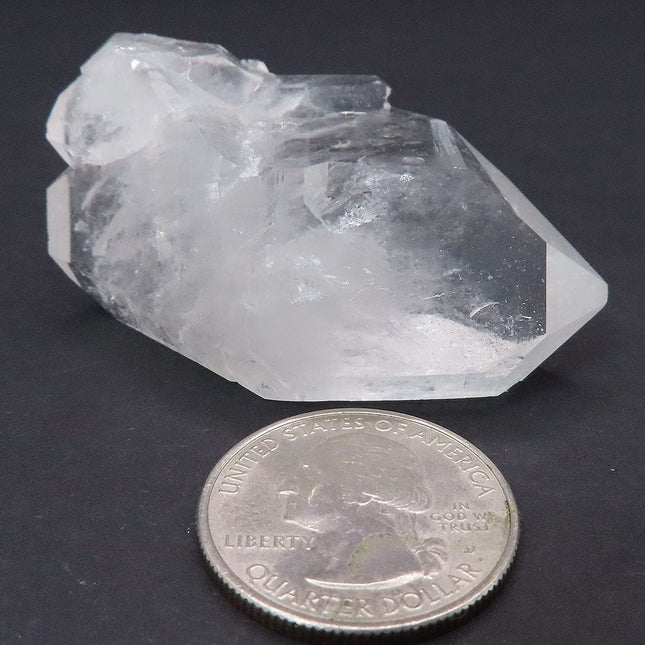 Arkansas Arkimer Style Quartz Crystal Double Terminated Point next to a quarter for scale on a dark background