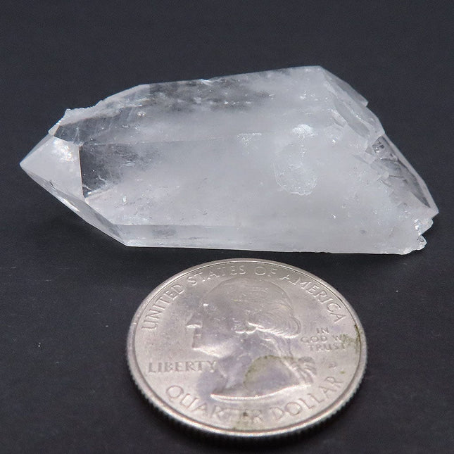 Arkansas Quartz Crystal Double Terminated Tabby Point with Self-Healed Elestial Face next to a quarter for scale on a dark background