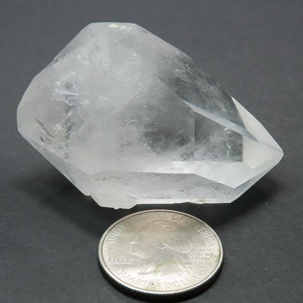 Arkansas Quartz Crystal Double Terminated Point next to a quarter for scale on a grey background