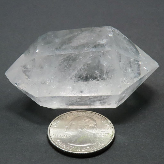Arkansas Quartz Crystal Double Terminated Point next to a quarter for scale on a grey background