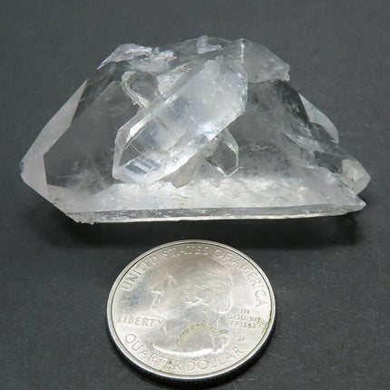 Arkansas Quartz Crystal Double Terminated/ET Point next to a quarter for scale on a grey background