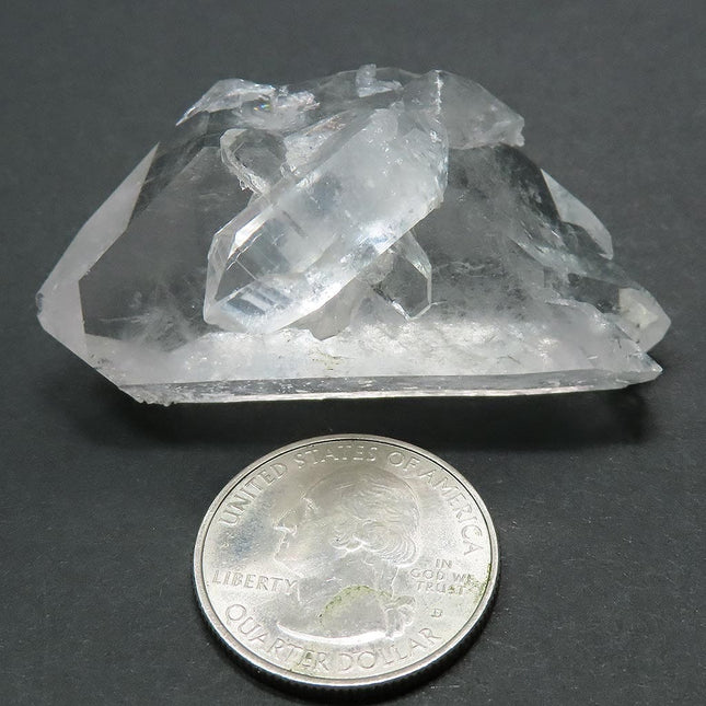 Arkansas Quartz Crystal Double Terminated/ET Point next to a quarter for scale on a grey background