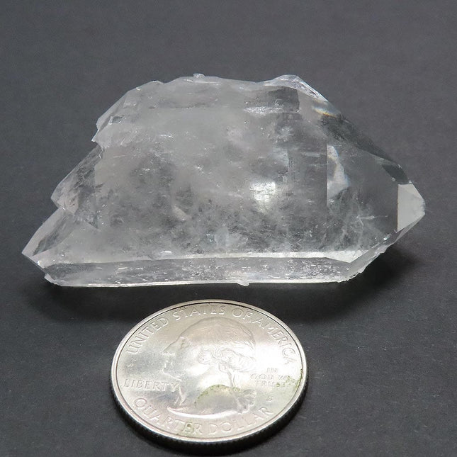 Arkansas Quartz Crystal Double Terminated/ET Point next to a quarter for scale on a grey background