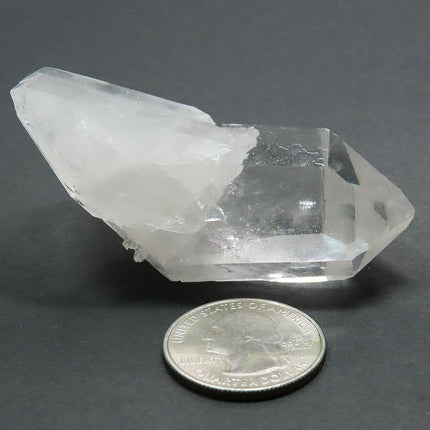 Arkansas Quartz Crystal Double Terminated Point next to a quarter for scale on a grey background