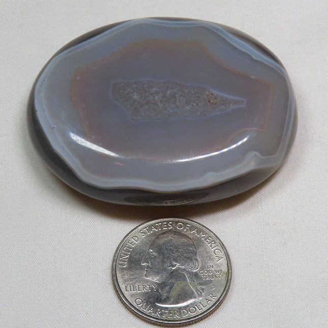 Polished Banded Agate Palm Stone from Madagascar next to a U.S. quarter dollar coin for scale on a white background
