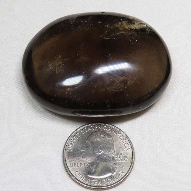 Polished Smoky Quartz Palm Stone from Brazil with Rainbow next to a U.S. quarter dollar on a white background