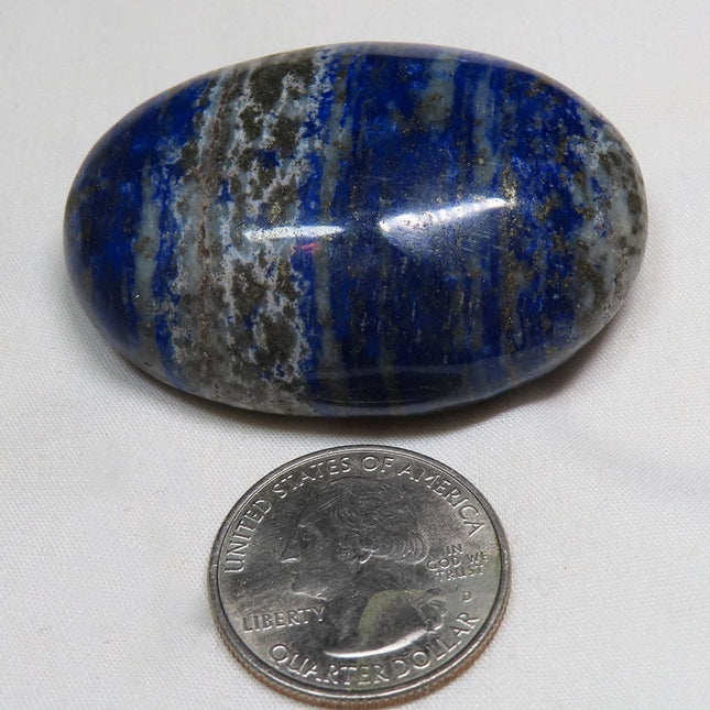 Polished Lapis Palm Stone from Afghanistan next to a U.S. quarter dollar for scale on a white background