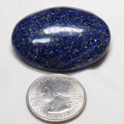 Polished Lapis Palm Stone from Afghanistan next to a U.S. quarter dollar for scale on a white background