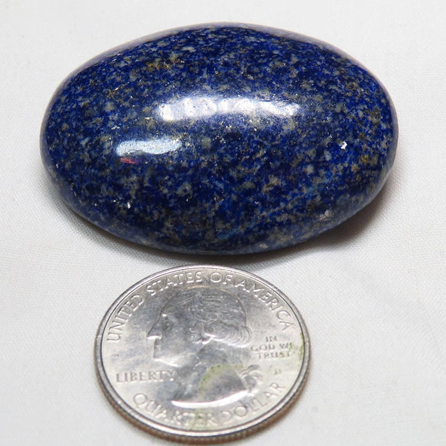 Polished Lapis Palm Stone from Afghanistan next to a U.S. quarter dollar for scale on a white background