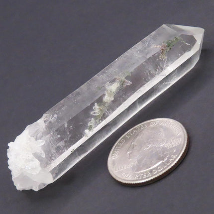 Included Clear Lemurian Seed Quartz Crystal Point with Record Keepers next to a quarter on a dark surface