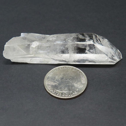Arkansas Quartz Crystal Grounding Point that is Etched next to a US quarter on a dark background