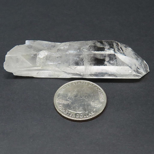 Arkansas Quartz Crystal Grounding Point that is Etched next to a US quarter on a dark background