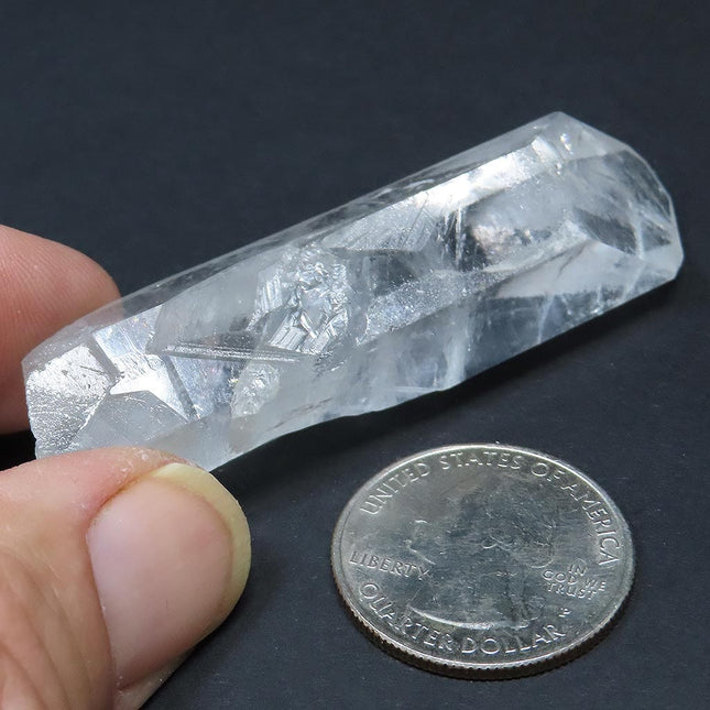 Arkansas Quartz Crystal Grounding Point that is Etched next to a US quarter on a dark background