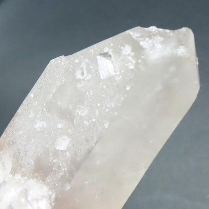 Close-up of a Ding on an Arkansas Metaphysical Delight Quartz Crystal Double Terminated/ET Point with Faden-Line with a gray background