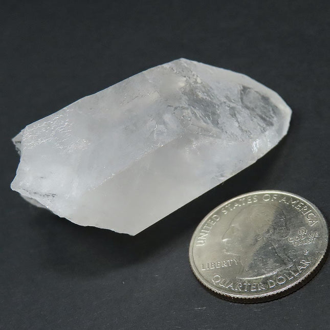 Arkansas Quartz Crystal Point that is Etched against a dark background next to a U.S. quarter dollar on a dark background