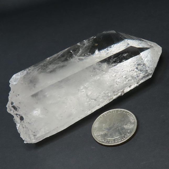 Arkansas Quartz Crystal Tabby Point with Manifestation next to a US quarter for scale on a dark background