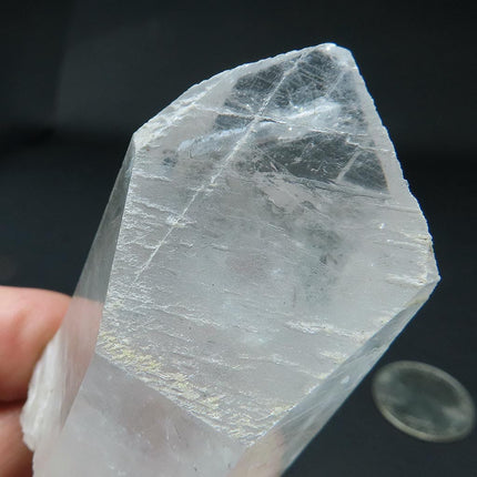 Arkansas Metaphysical Delight Quartz Crystal Point held by a hand against a dark background