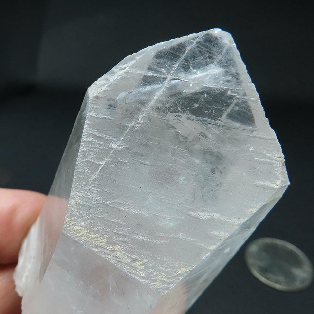 Arkansas Metaphysical Delight Quartz Crystal Point held by a hand against a dark background