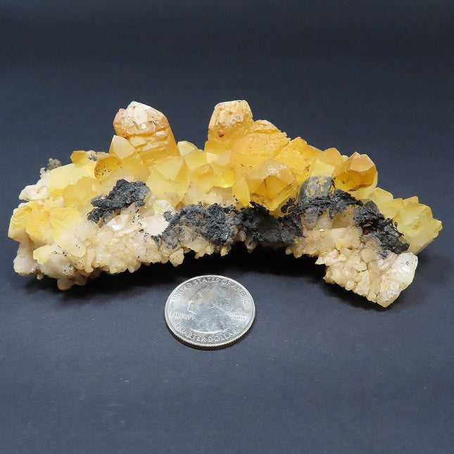 Arkansas Natural Uncleaned Quartz Crystal Burr Cluster w/ Iridescence on a dark background, compared to a quarter for scale.