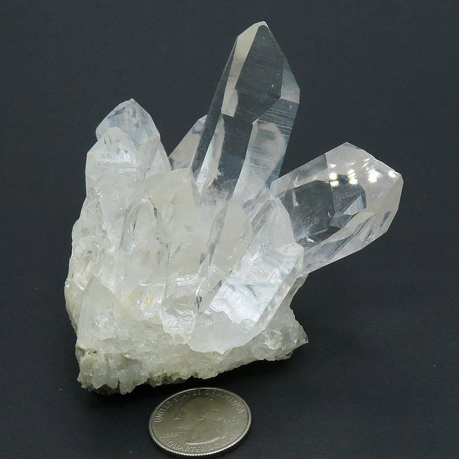 Arkansas Quartz Crystal Cluster with Two Time-Link Activations and a quarter for scale on a dark background