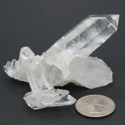 Arkansas Quartz Crystal Cluster with a quarter for scale on a dark background
