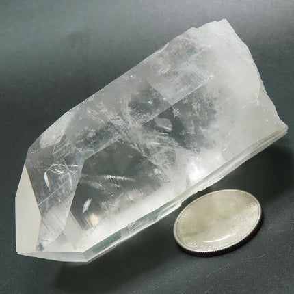 Arkansas Quartz Crystal Point with Record Keeper Triangles next to a US quarter for scale on a dark surface
