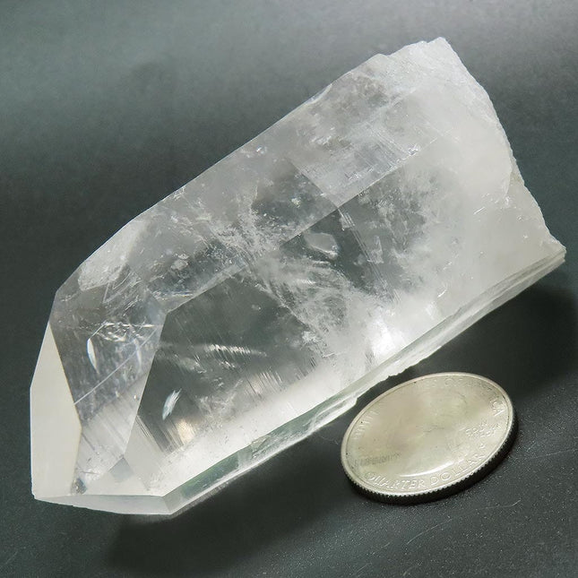 Arkansas Quartz Crystal Point with Record Keeper Triangles next to a US quarter for scale on a dark surface