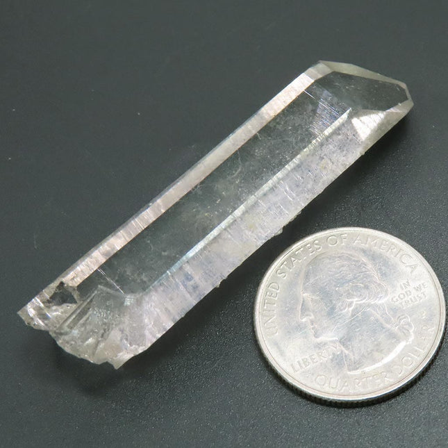Arkansas Quartz Crystal Point next to a U.S. quarter for scale on a dark surface
