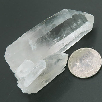 Arkansas Quartz Crystal Point next to a U.S. quarter for scale on a dark surface