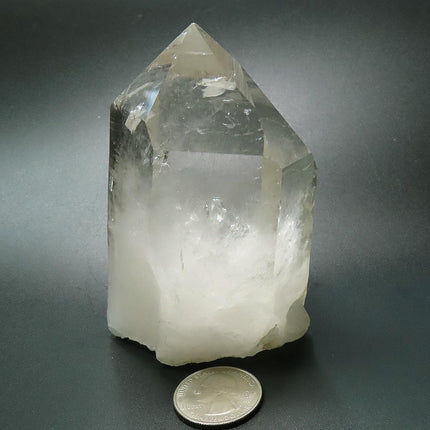 Arkansas Quartz Crystal Point with Rainbow with a US quarter for scale on a dark background