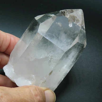Arkansas Quartz Crystal Point with Rainbow with a US quarter for scale on a dark background