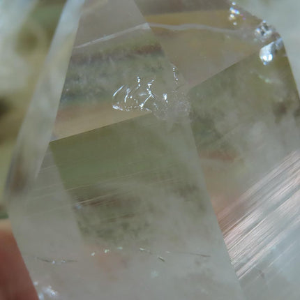 Ding on Arkansas Quartz Crystal Point with Rainbow with a US quarter for scale on a dark background