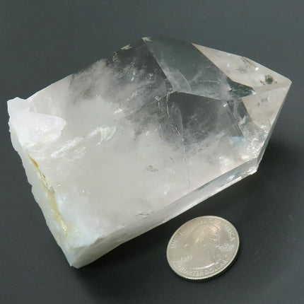 Arkansas Quartz Crystal Point with Rainbow with a US quarter for scale on a dark background