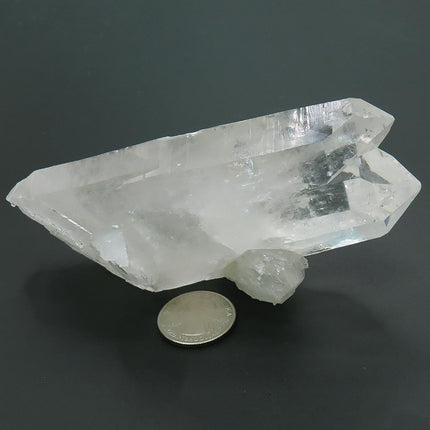 Arkansas Quartz Crystal Twin Soulmate Point and a US quarter for scale on a dark background