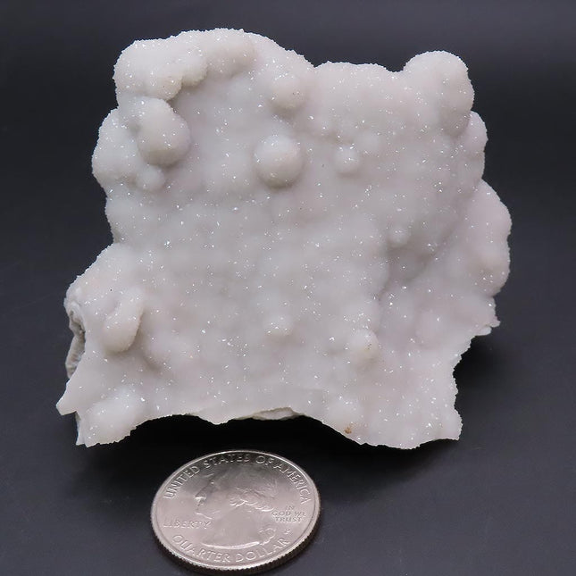 Sparkling Silver Grey Botryoidal Drusy Quartz Specimen from Missouri with a quarter for scale on a dark background