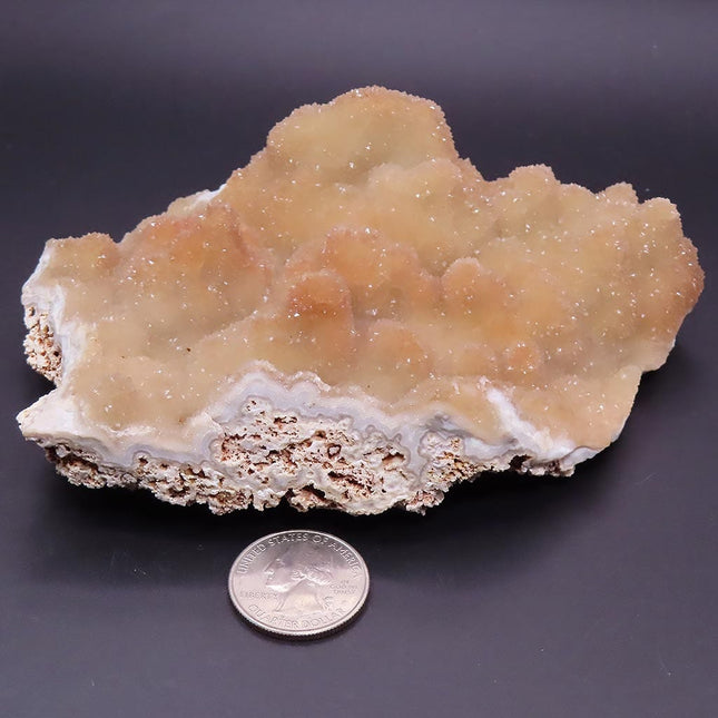Sparkling Peach Pink Botryoidal Drusy Quartz Specimen from Missouri with a quarter for scale on a dark background