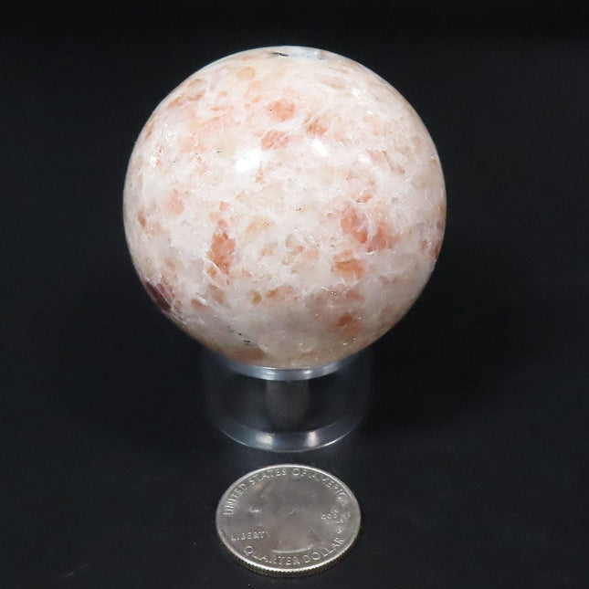 Polished Sunstone Sphere Ball from India with a quarter for scale on a black background