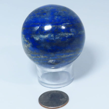 Polished Lapis Sphere Ball from Afghanistan on a clear stand with a quarter for scale on a light gray background