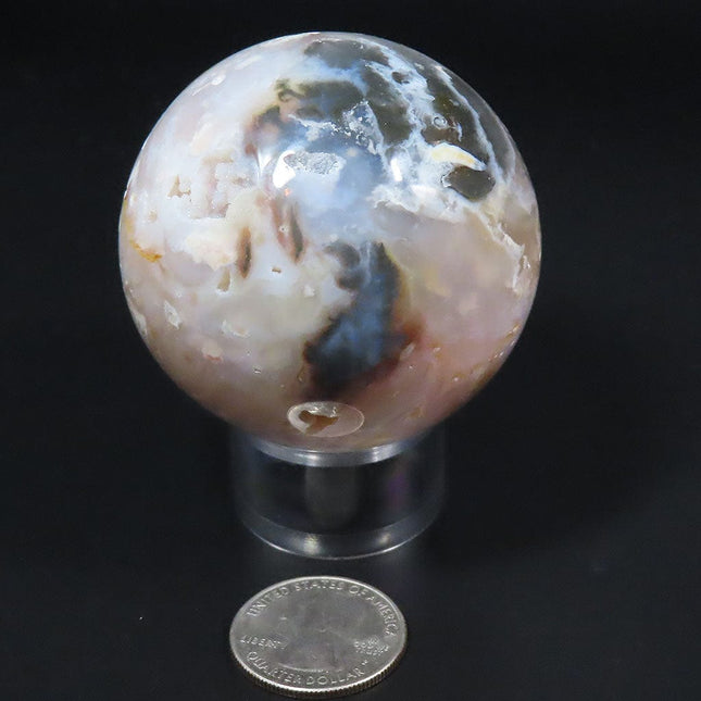 Polished Purple Chalcedony Sphere Ball from Mexico on a stand with a USA quarter for scale against a black background