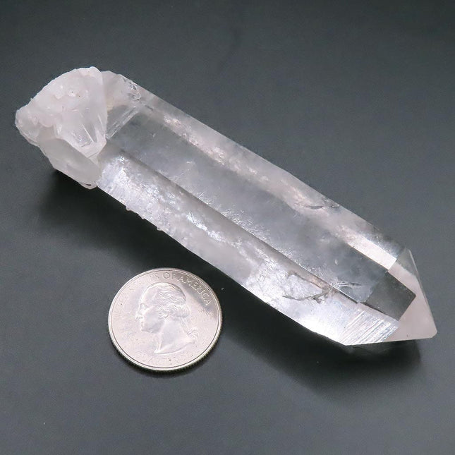 Arkansas Quartz Crystal Point next to a U.S. quarter on a dark surface