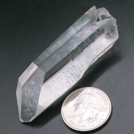 Arkansas Quartz Crystal Point with Record Keeper Triangles next to a quarter on a dark background