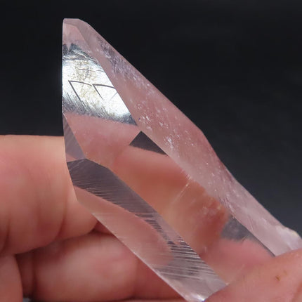 Clear crystal with Record Keeper Triangles held between fingers against a dark background